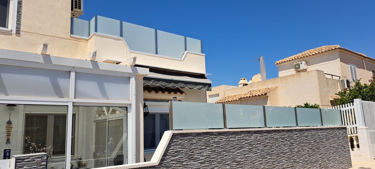 Una casa con una valla de cristal delante de ella.