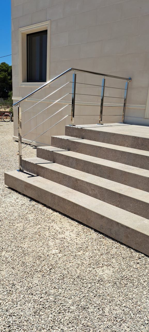 Un conjunto de escaleras que conducen a un edificio con barandilla de acero inoxidable.