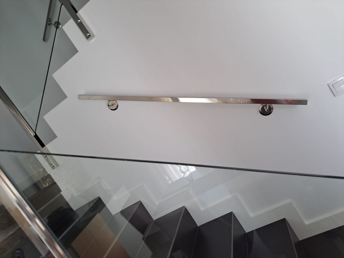 Una escalera con barandilla de acero inoxidable y barandilla de vidrio.