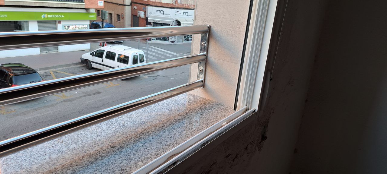 Una vista de una calle desde una ventana con barandilla de acero inoxidable.