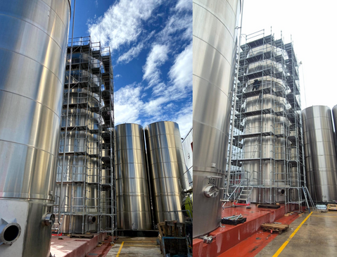 Grands réservoirs industriels en acier inoxydable, entourés d'échafaudages, sur fond de ciel 