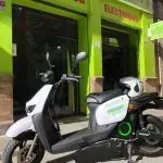 Un scooter está estacionado delante de un edificio verde.