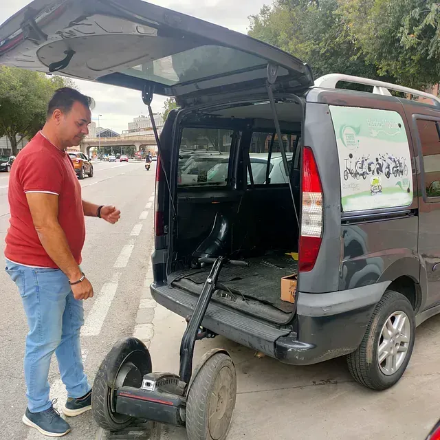 Un hombre está de pie junto a una camioneta con el maletero abierto.
