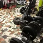 Una fila de segways están colocados sobre un suelo de baldosas en un garaje.