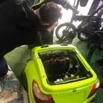 Un hombre está trabajando en el motor de un coche amarillo.