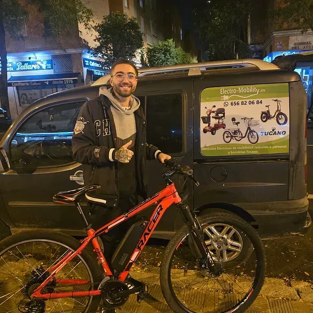 Un hombre parado junto a una bicicleta frente a una camioneta.