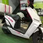 Un scooter blanco está estacionado sobre una alfombra verde en una habitación.