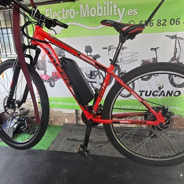Una bicicleta roja está estacionada frente a un cartel que dice tucano