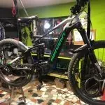 Una bicicleta está aparcada en un garaje al lado de una pared verde.