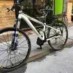 Una bicicleta blanca está estacionada al costado de la carretera.