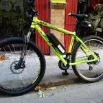 Una bicicleta verde está estacionada al costado de la carretera.