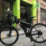 Una bicicleta está estacionada en la acera frente a una tienda.