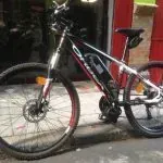 Una bicicleta está estacionada al costado de la carretera frente a un edificio rojo.