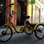 Una bicicleta amarilla con tres ruedas está estacionada frente a un edificio.