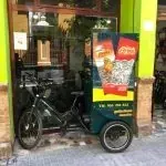 Una bicicleta con un carrito acoplado está estacionada frente a una tienda.