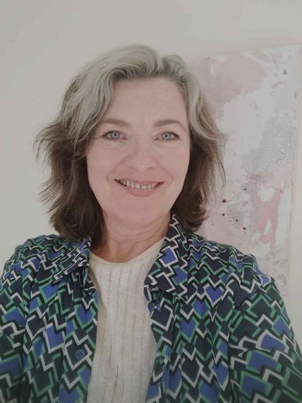 Una mujer con una chaqueta azul y verde sonríe a la cámara.