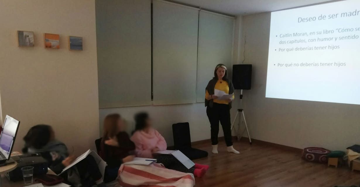 Una mujer está dando una presentación a un grupo de personas en una habitación.