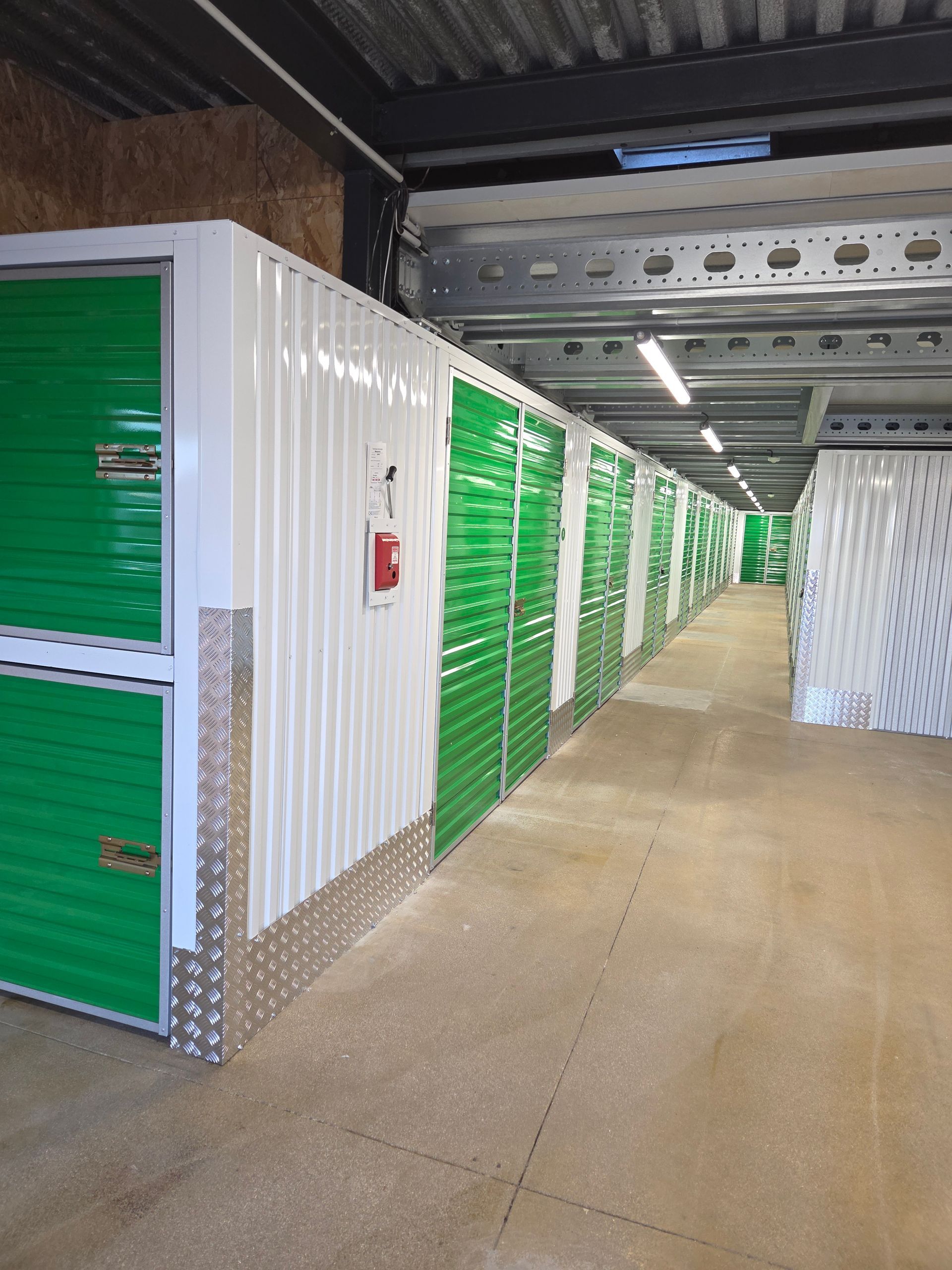 Une personne transporte un carton dans un box de stockage contenant des cartons empilés.