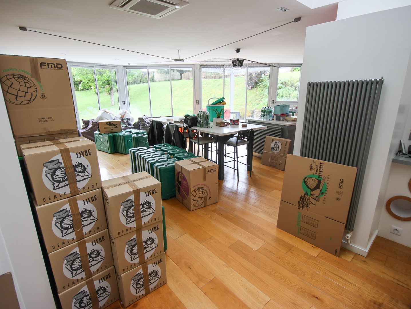 Bureau vide avec des bureaux, des chaises à roulettes et des cartons emballés dans du plastique près de grandes fenêtres.