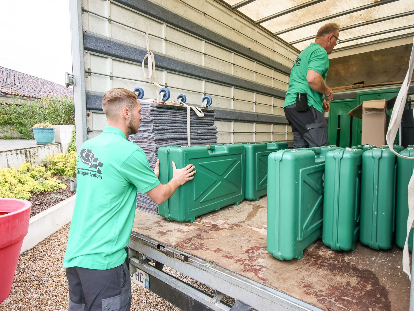 Deux déménageurs chargent des cartons dans une camionnette blanche.