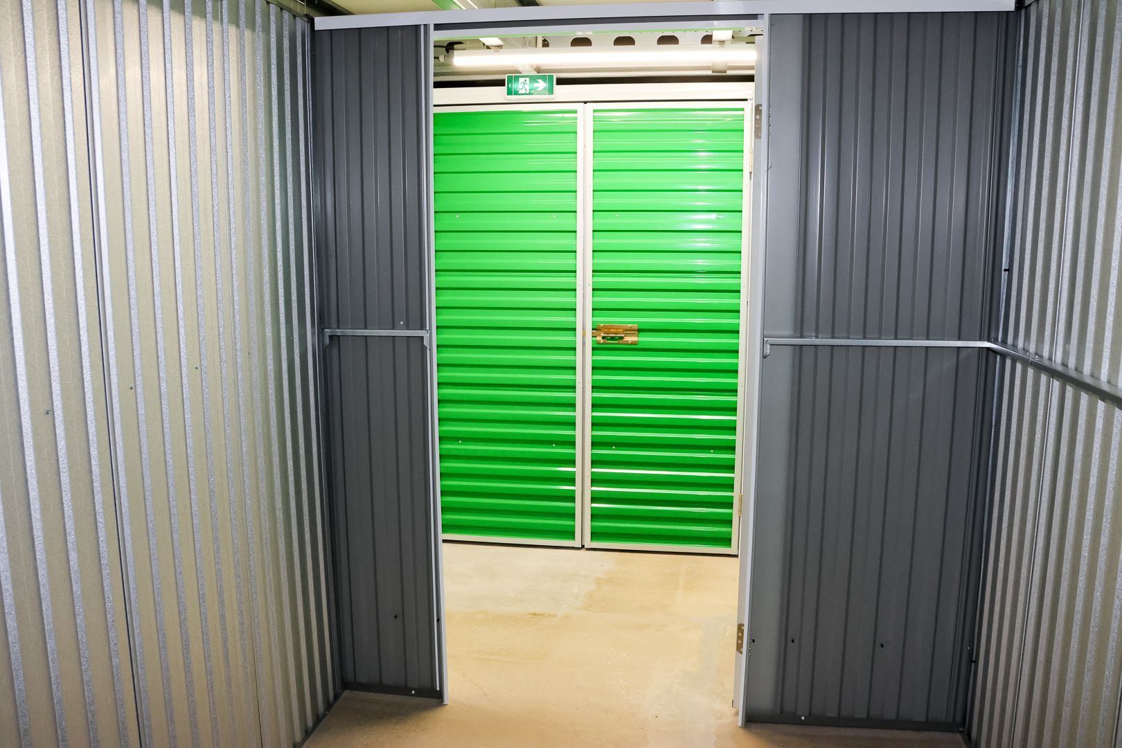 Deux déménageurs transportent des cartons dans un box de stockage avec des bacs rouges et un diable.