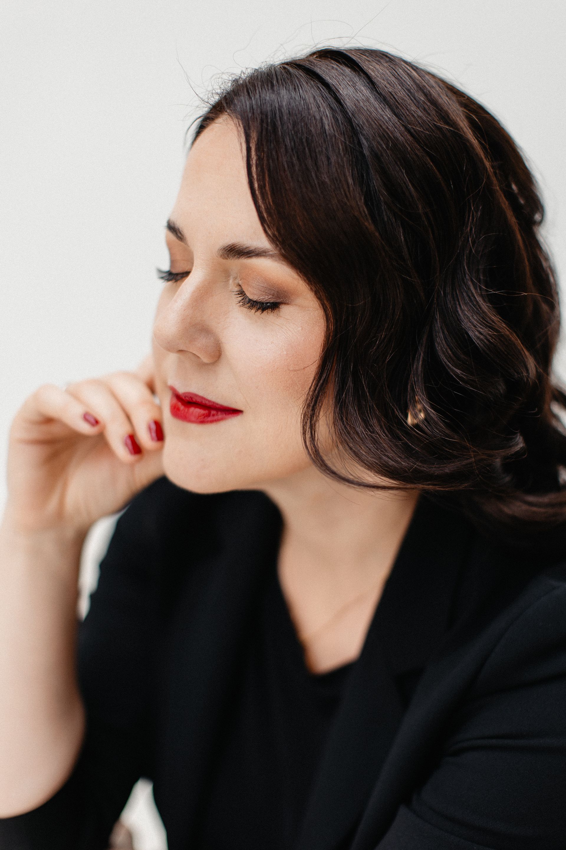 Frau mit dunklen Haaren und rotem Lippenstift im Profil mit geschlossenen Augen