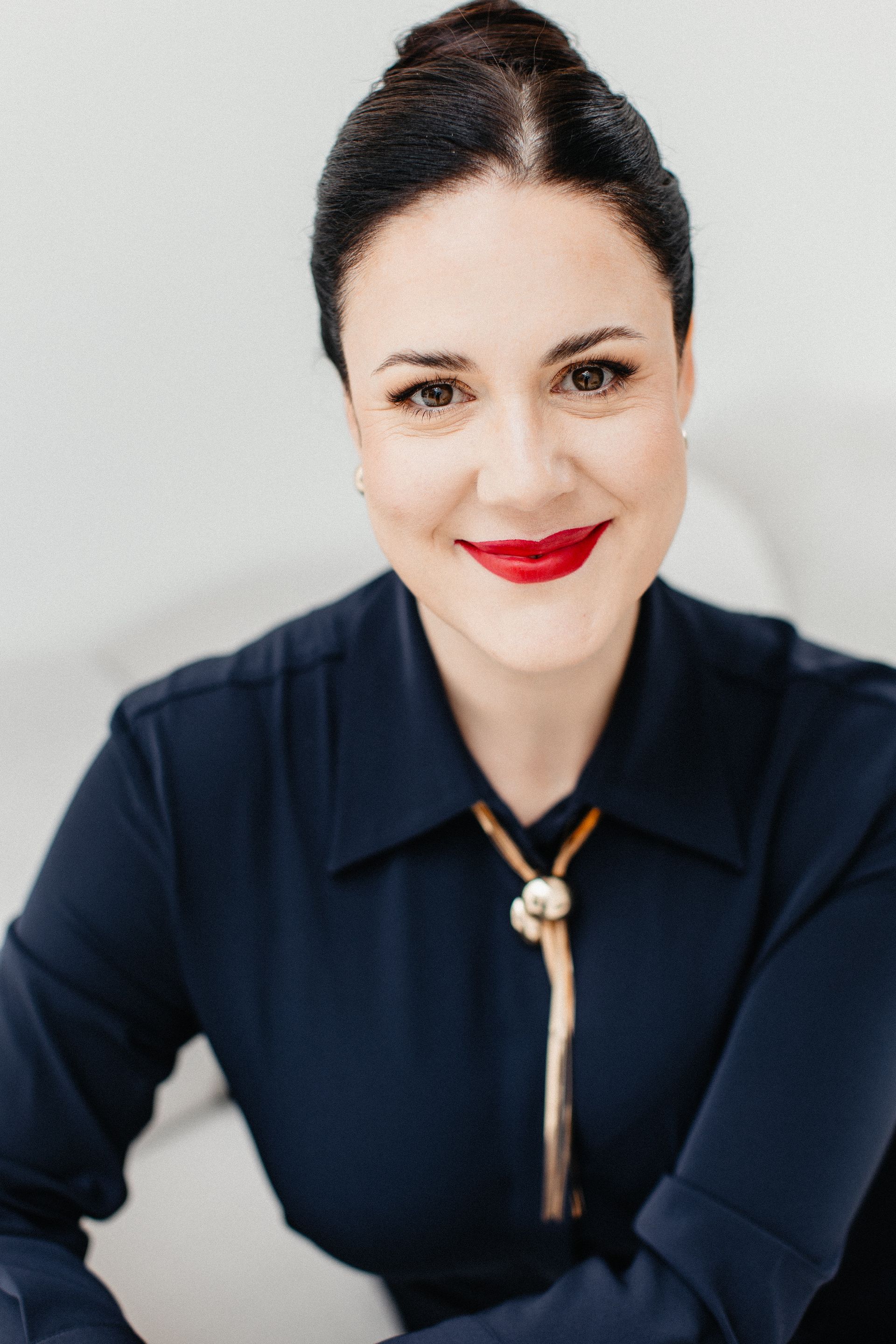 Portrait von lächelnder Frau in blauem Kleid mit hochgesteckten Haaren