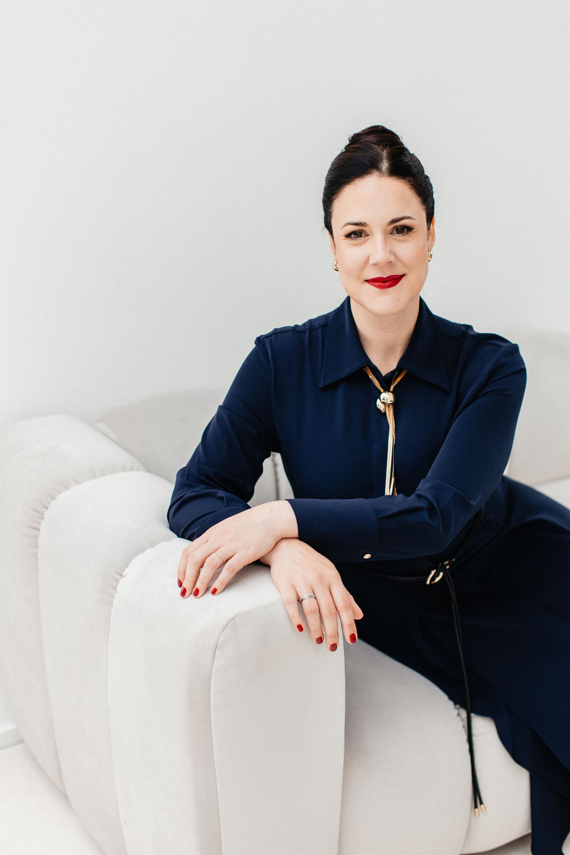 Frau in blauem Kleid sitzt auf weissem Sofa