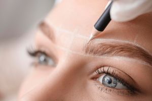 Einer Frau werden die Augenbrauen mit einem Bleistift nachgezogen.