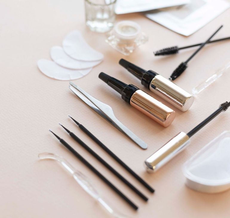 Zwei Flaschen Mascara und eine Pinzette auf einem Tisch