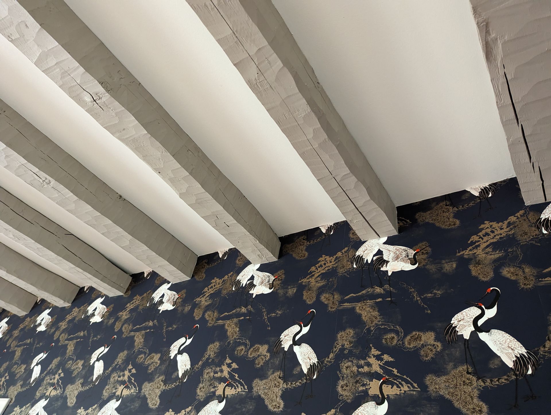 Chambre avec fresque de flamants roses, rideaux roses, bureau blanc, lit, télévision et vue sur la ville.