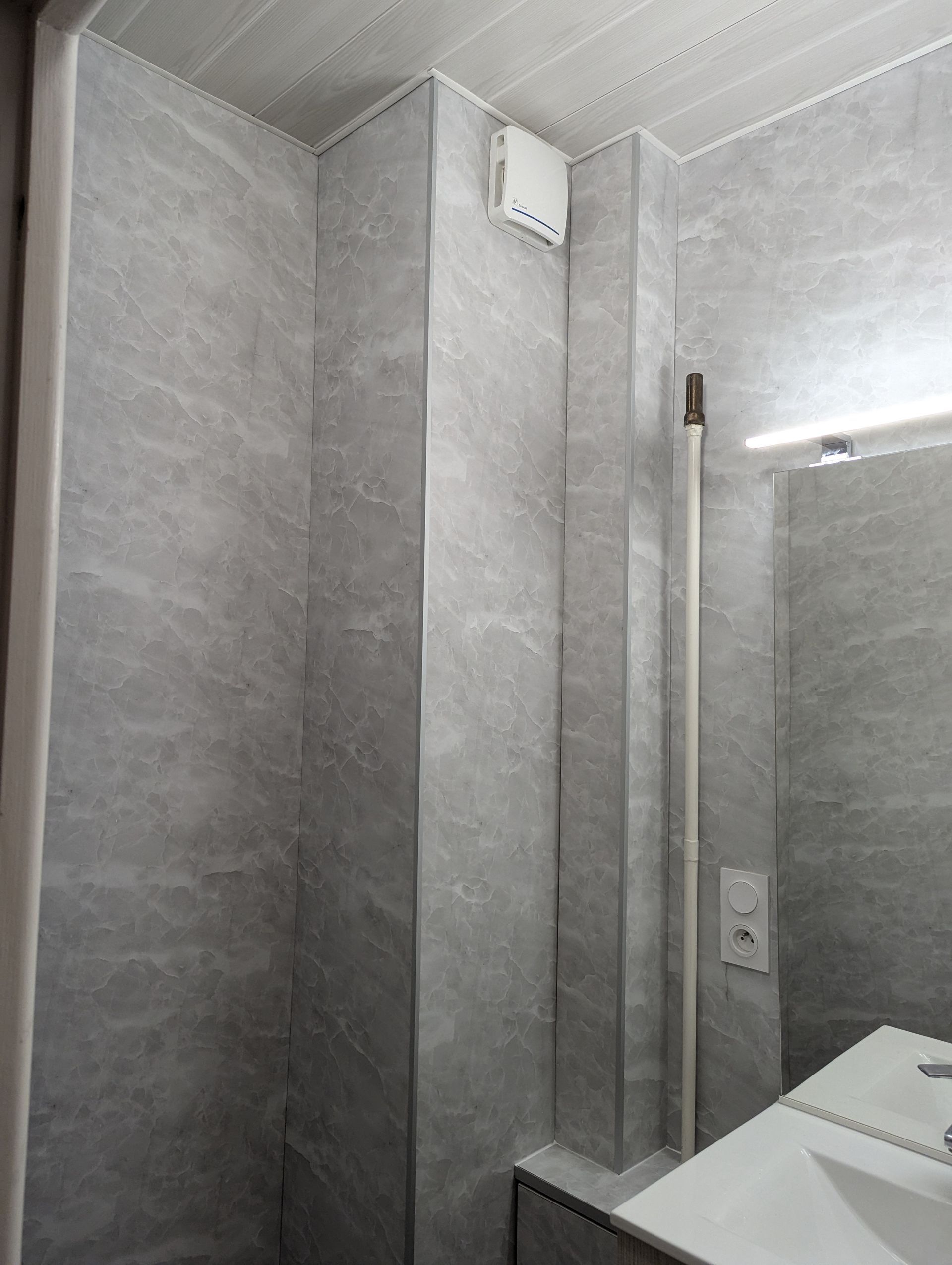 Table de chevet avec lampe, œuvre d'art et lit. La lampe éclaire la table.