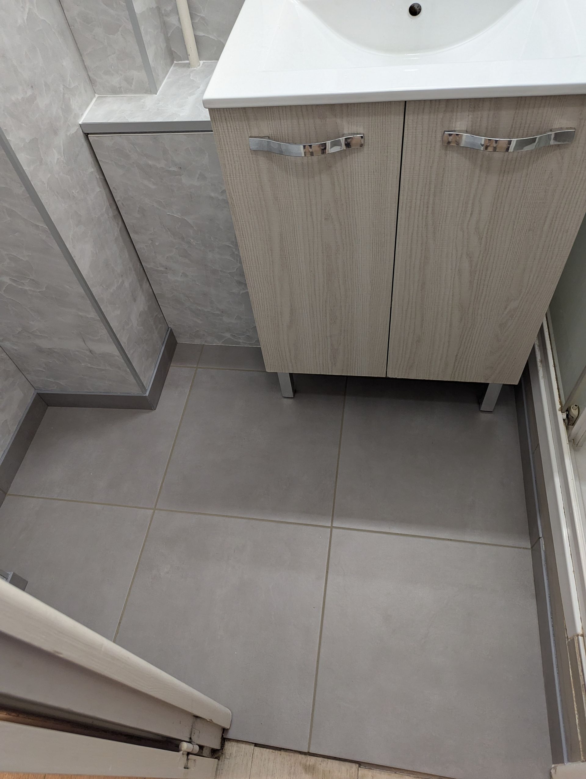 Escalier aux marches et rampes grises, montant contre un mur clair.