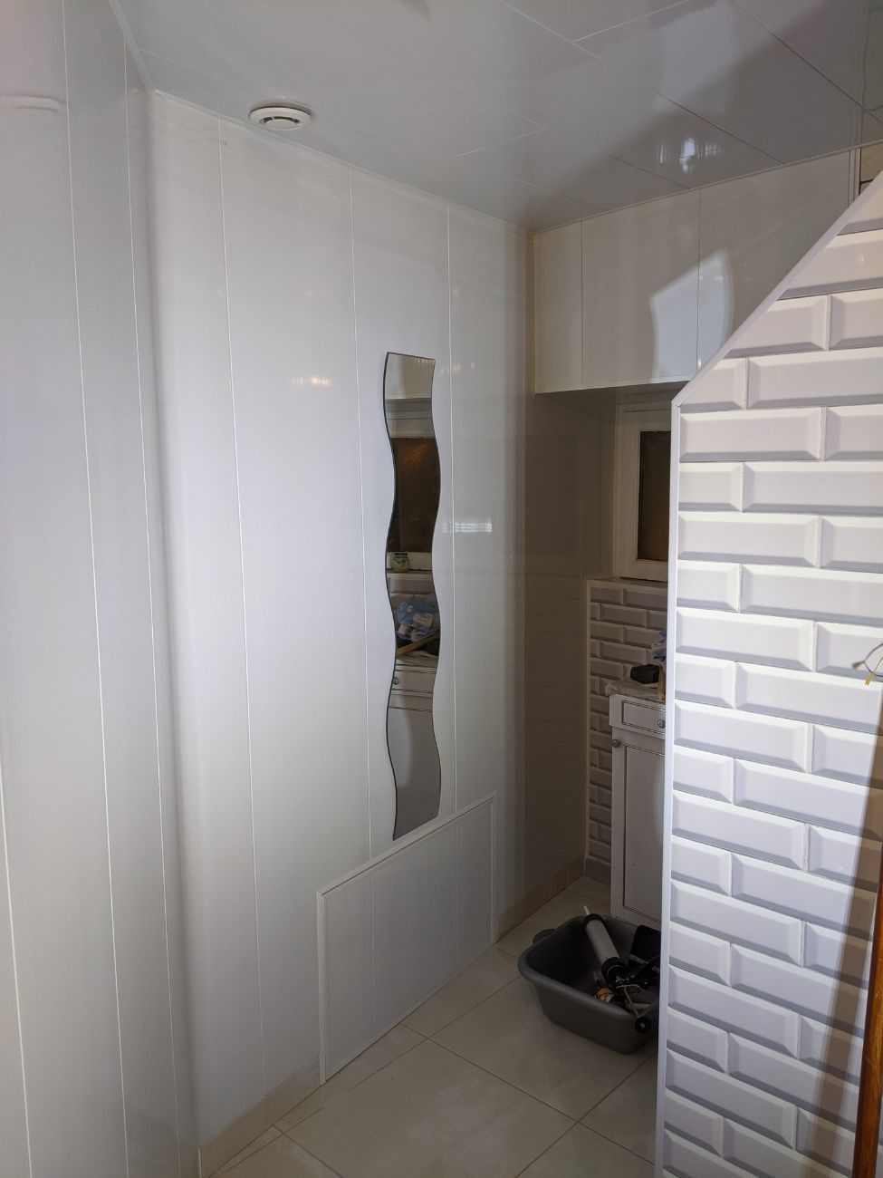 Vue intérieure d'une pièce avec un grand trou dans un mur lambrissé blanc.