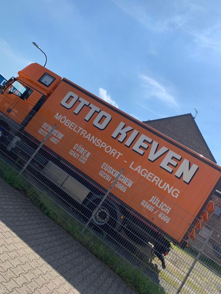 Ein orangefarbener Otto-Kieven-Truck steht neben einem Zaun