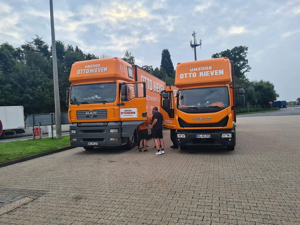 Ein Mann steht neben zwei Lastwagen, die sagen: „By to to mover“