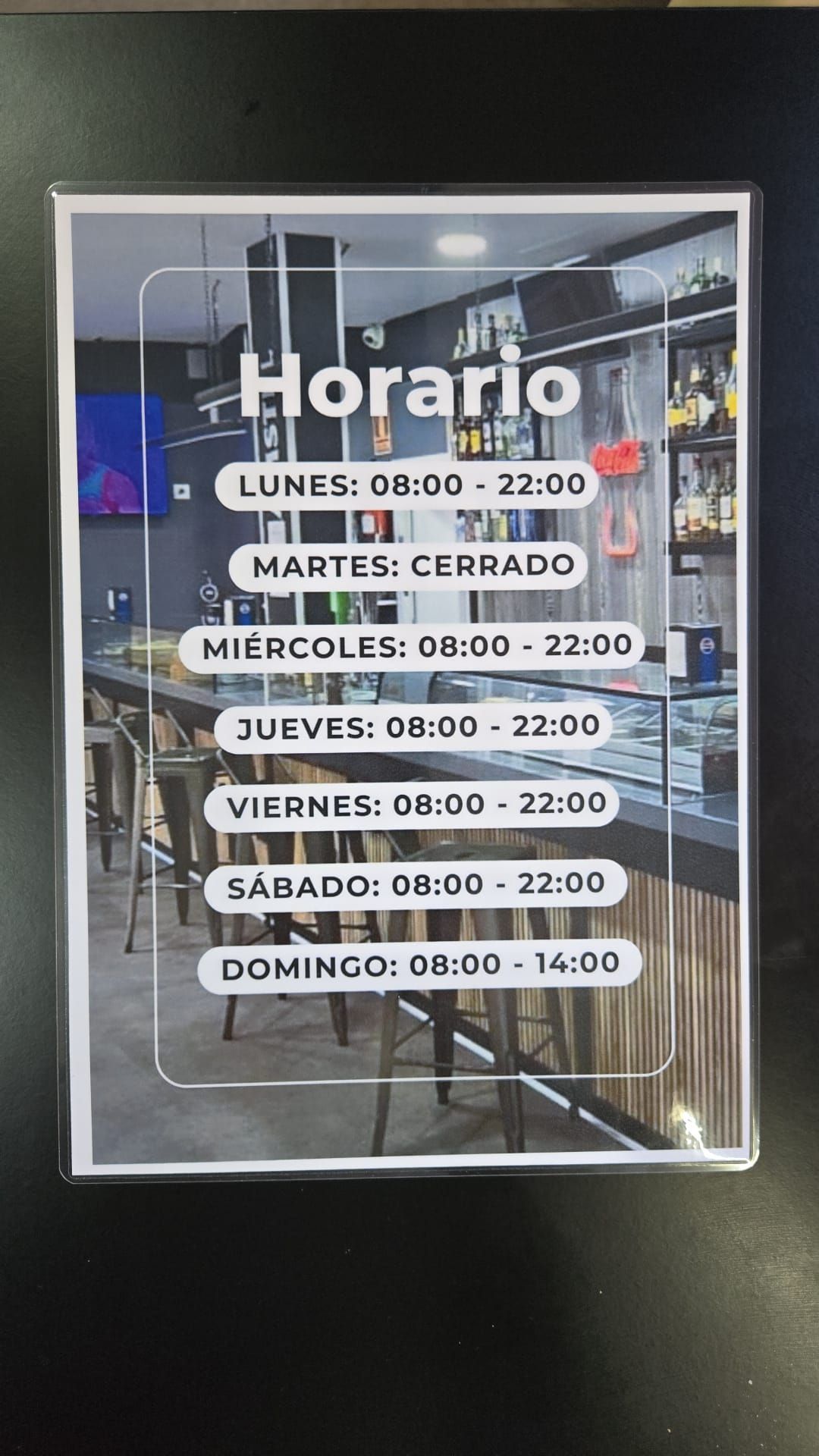 Un cartel que indica el horario comercial: lunes a sábado de 8:00 a 22:00, domingo de 8:00 a 14:00 y martes cerrado.