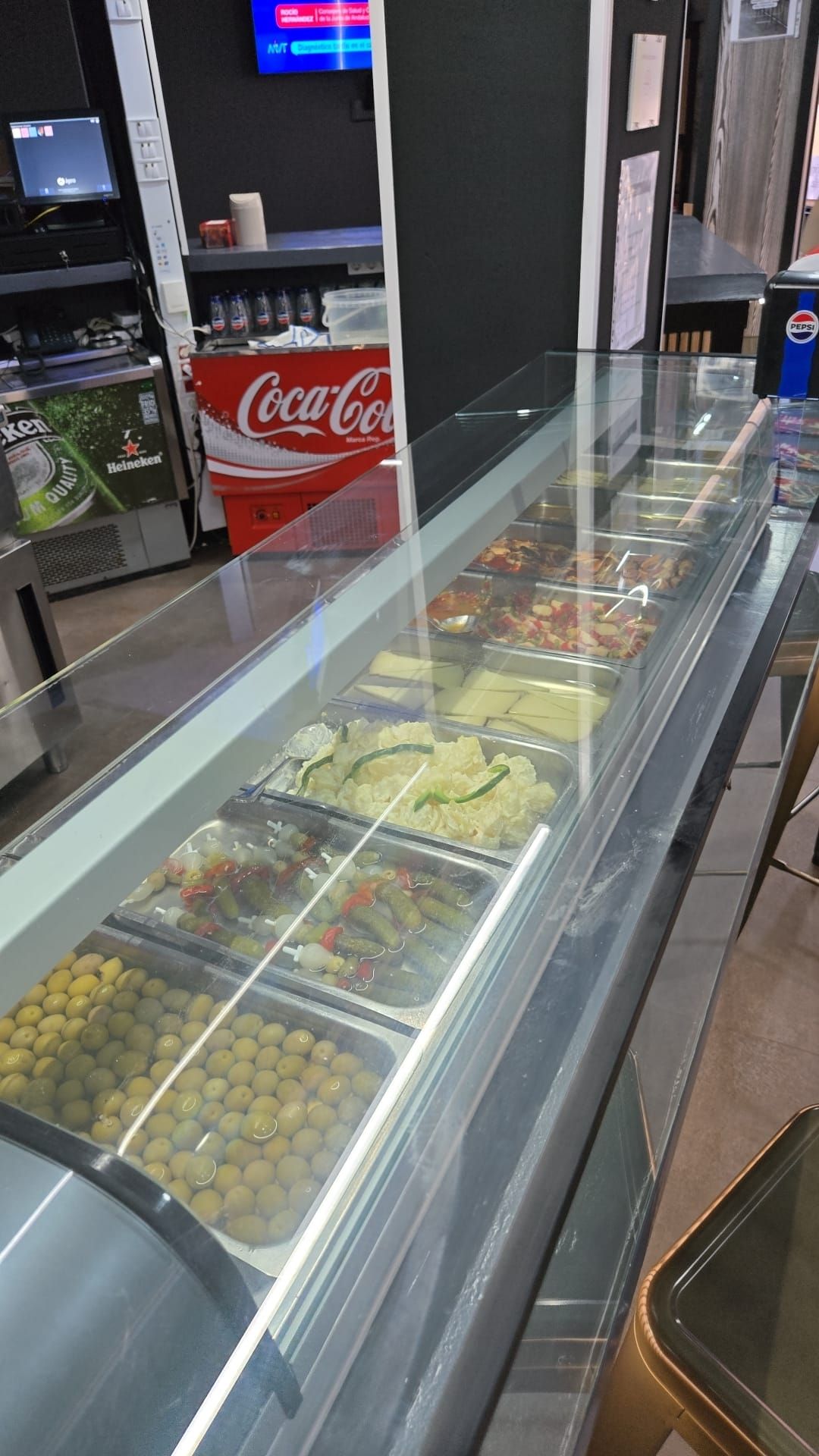 Vitrina alargada llena de alimentos preparados; ambiente de restaurante.