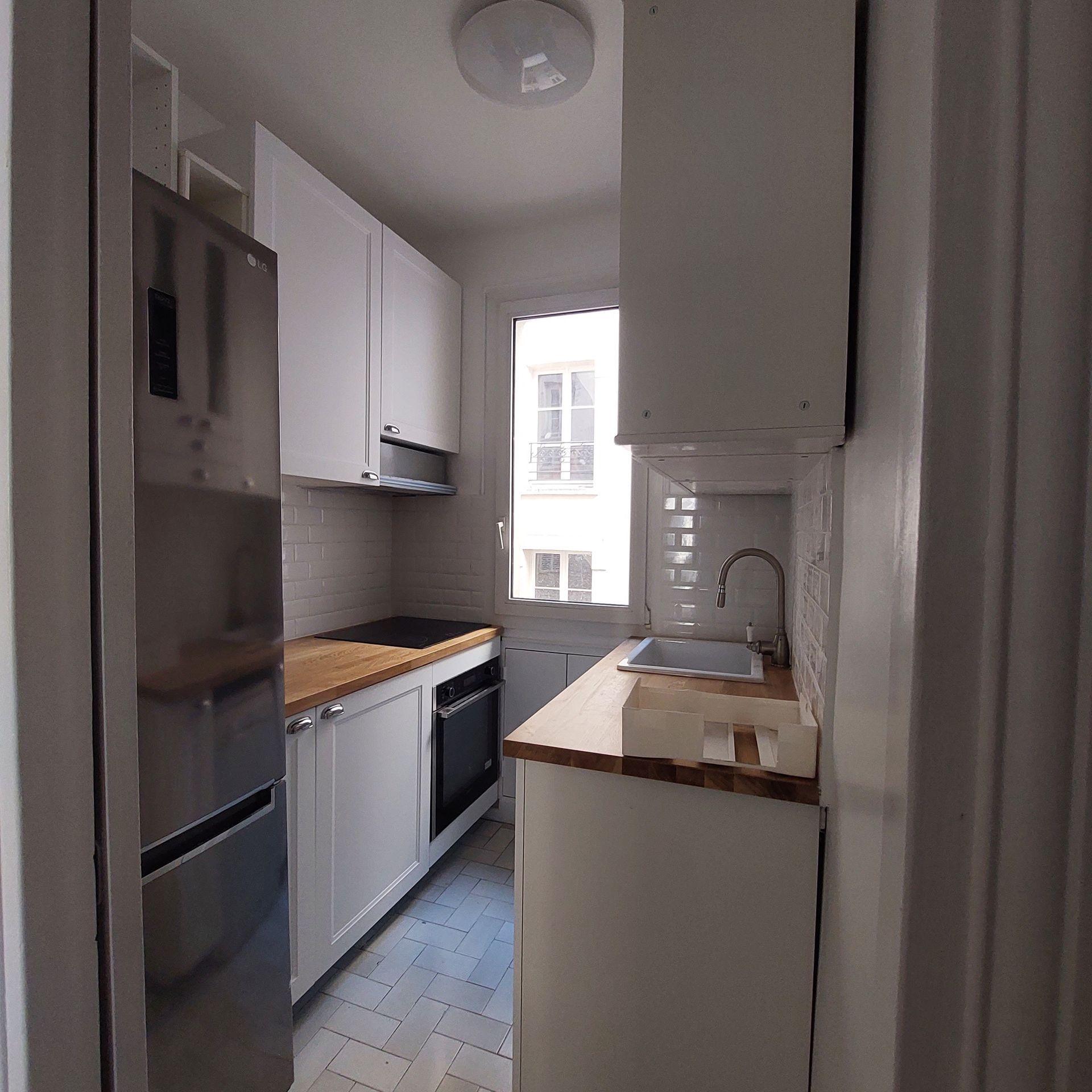 Une cuisine rénovée avec un plan de travail en bois et des meubles sur mesure.