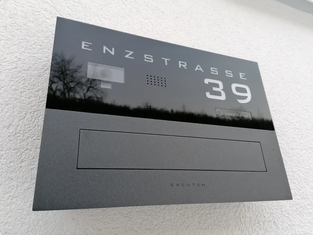 Mauerdurchwurf-Briefkasten durchwurf-Briefkasten 1-Familien von ERCOTEH mit Videosprechanlage in Anthrazit RAL 7016 Edelstahl, beleuchtete Straße und Hausnummer mit eingebauter Kamera und Klingel Fingerprint Codeschloss und keypad Türsprechanlage von Gira System 106, Siedle, Loxone, 2N, HIKVISION Videosprechanlage maßanfertigung nach kundenwunsch aufputz briefkasten designer premium ercoteh briefkastenmanufaktur made in germany set 2009
