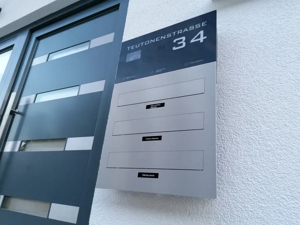Mauerdurchwurf-Briefkasten durchwurf-Briefkasten 3-Familien von ERCOTEH mit Videosprechanlage in Anthrazit RAL 7016 Edelstahl, beleuchtete Straße und Hausnummer mit eingebauter Kamera und Klingel Fingerprint Codeschloss und keypad Türsprechanlage von Gira System 106, Siedle, Loxone, 2N, HIKVISION Videosprechanlage maßanfertigung nach kundenwunsch aufputz briefkasten designer premium ercoteh briefkastenmanufaktur made in germany set 2009