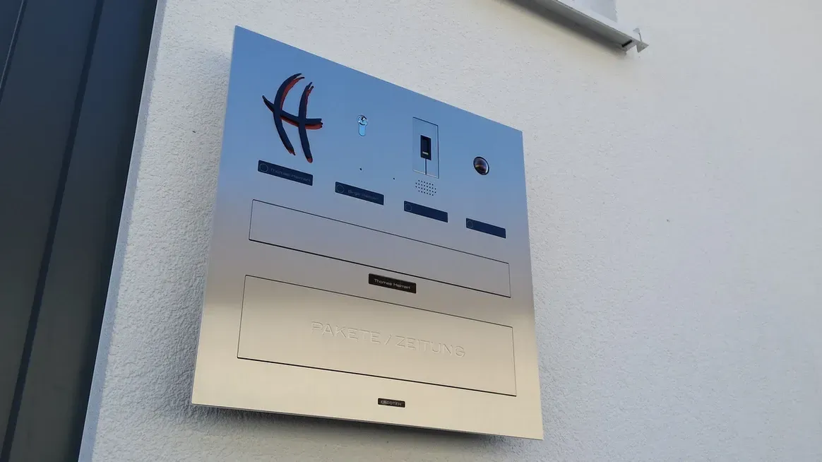 Mauerdurchwurf-Briefkasten durchwurf-Briefkasten 1-Familien von ERCOTEH mit Videosprechanlage in Anthrazit RAL 7016 Edelstahl, beleuchtete Straße und Hausnummer mit eingebauter Kamera und Klingel Fingerprint Codeschloss und keypad Türsprechanlage von Gira System 106, Siedle, Loxone, 2N, HIKVISION Videosprechanlage maßanfertigung nach kundenwunsch aufputz briefkasten designer premium ercoteh briefkastenmanufaktur made in germany set 2009