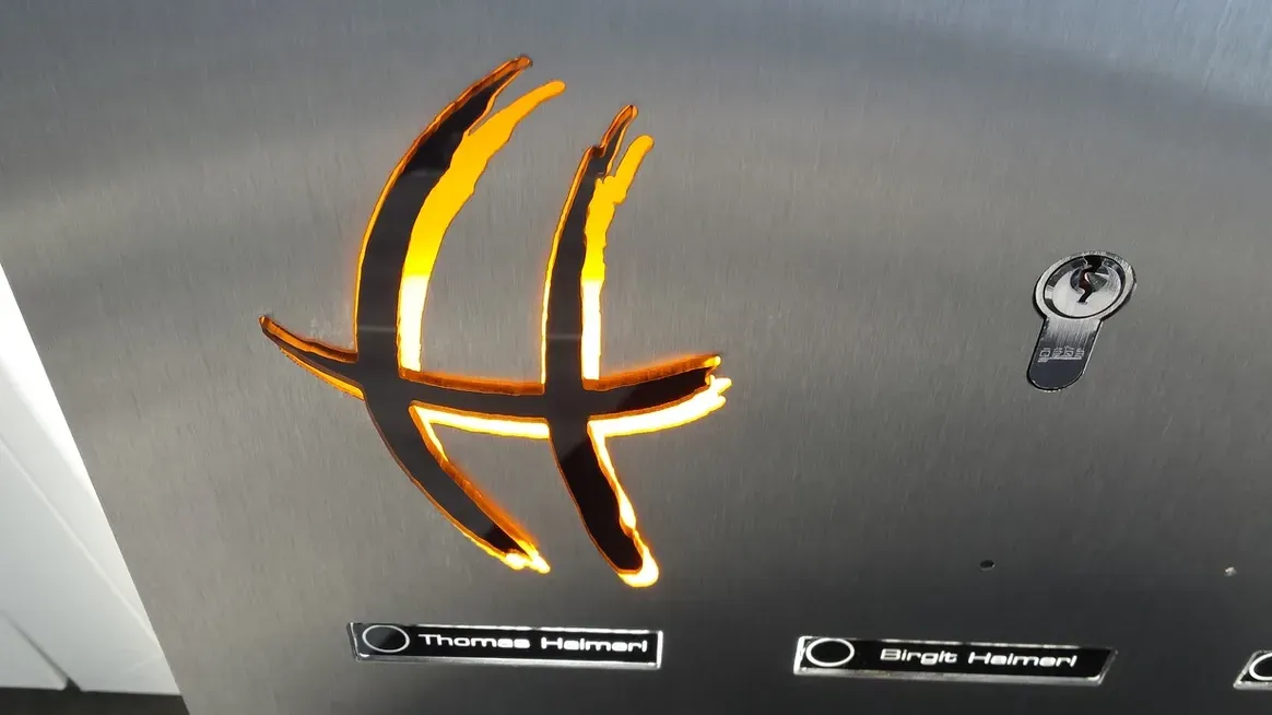 Mauerdurchwurf-Briefkasten Firmenlogo beleuchtet durchwurf-Briefkasten 1-Familien von ERCOTEH mit Videosprechanlage in Anthrazit RAL 7016 Edelstahl, beleuchtete Straße und Hausnummer mit eingebauter Kamera und Klingel Fingerprint Codeschloss und keypad Türsprechanlage von Gira System 106, Siedle, Loxone, 2N, HIKVISION Videosprechanlage maßanfertigung nach kundenwunsch aufputz briefkasten designer premium ercoteh briefkastenmanufaktur made in germany set 2009