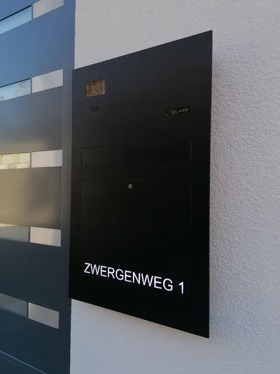 Ein schwarzes Schild an einer Wand mit der Aufschrift Zwergenweg 1