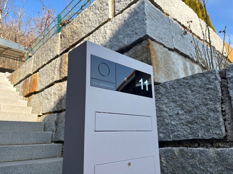 Vor einer Steinmauer steht ein Briefkasten mit der Nummer 11.