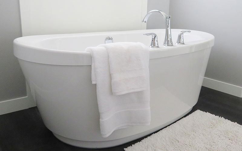 Eine Badewanne mit zwei Handtüchern, die in einem Badezimmer heraushängen.