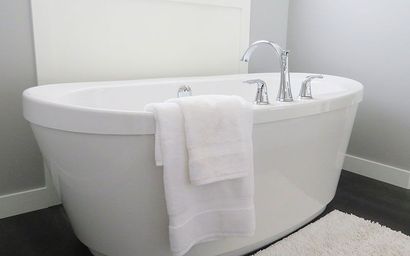 Eine weiße Badewanne mit zwei weißen Handtüchern darauf in einem Badezimmer.