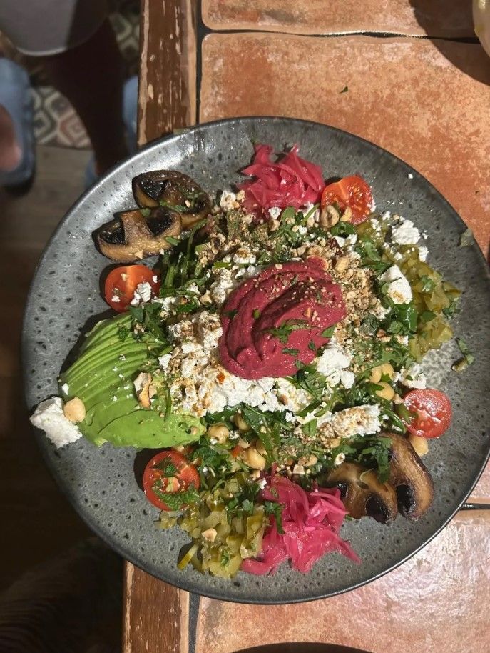 Plato con ensalada colorida: aguacate, hummus, queso feta, remolacha, tomates, champiñones.