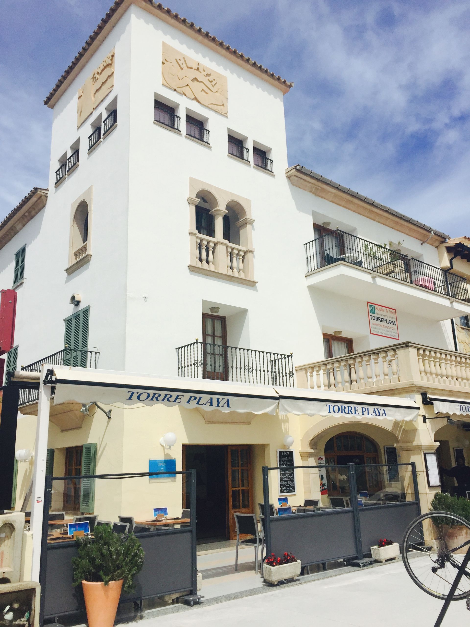 Restaurante frente a la playa con mesas, sillas y vista al océano bajo un toldo de madera.