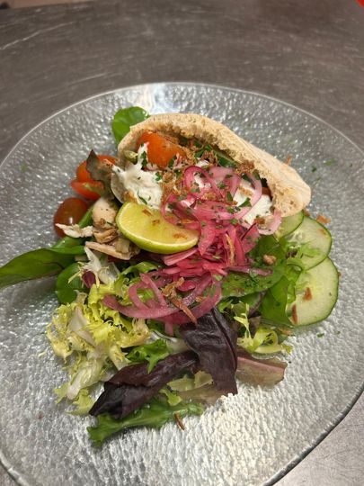 Ensalada con pita, verduras y cebollas encurtidas en un plato de vidrio.